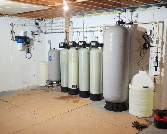 Whole-home water filtration system with filter tanks installed in a basement