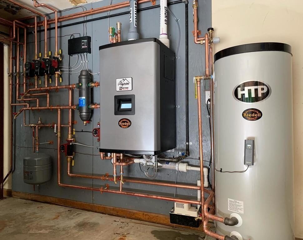 Wall-mounted HTP boiler connected to an indirect water heater storage tank with neat copper piping in a residential mechanical room